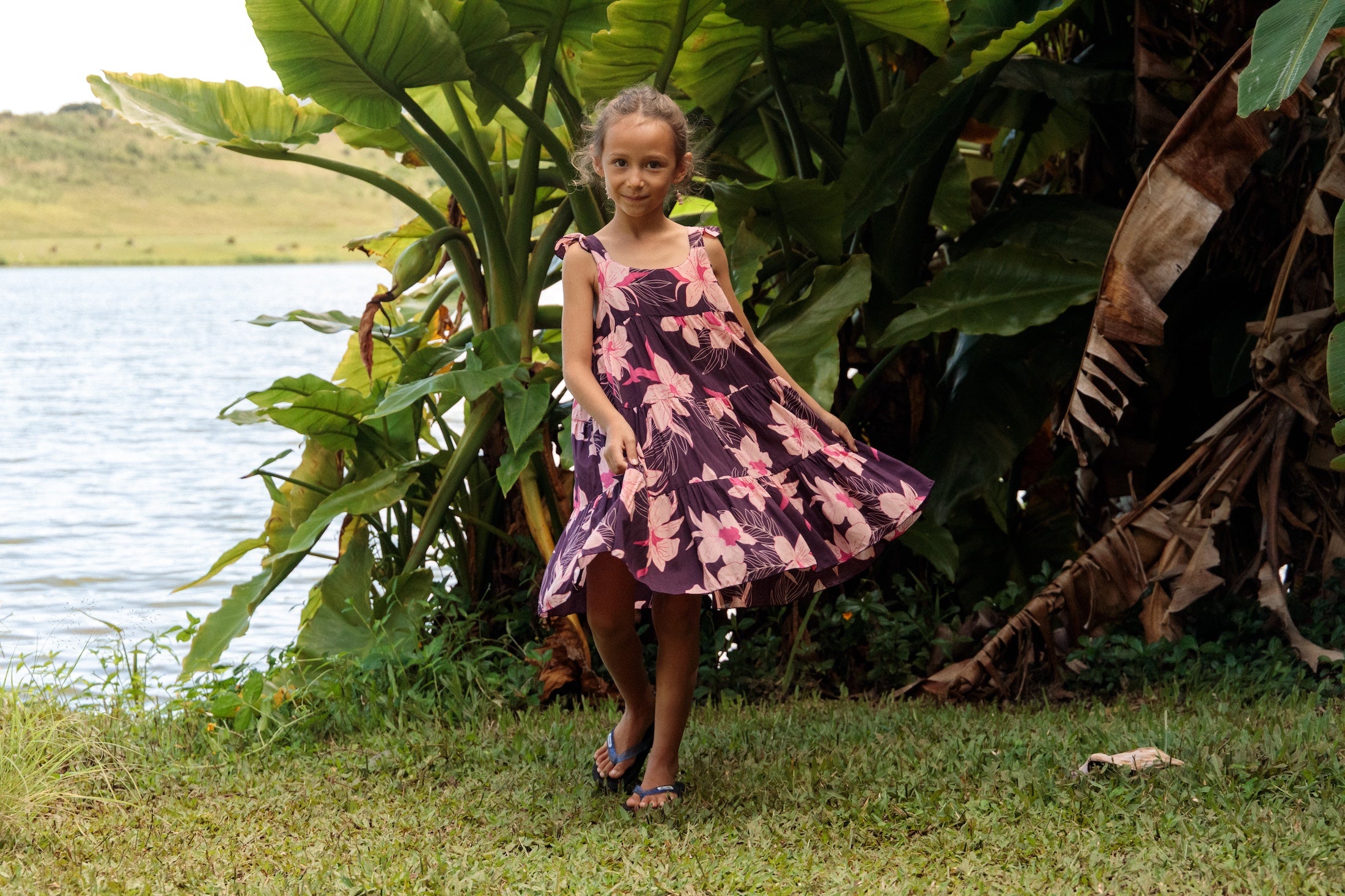little girl wearing dark purple dress with flutter sleeve and orchid print
