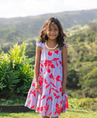 little girl with brown hair wearing a mid length dress with periwinkle background and bright red hibiscus print.