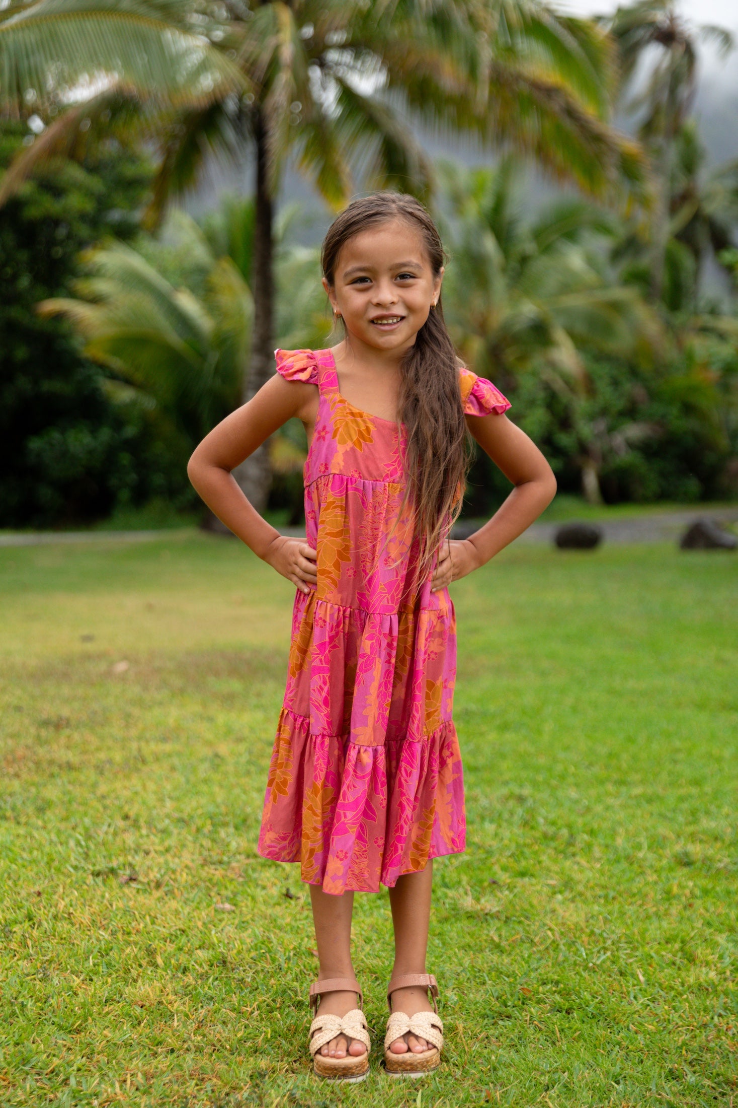little girl wearing a long pink tiered dress with ruffle straps
