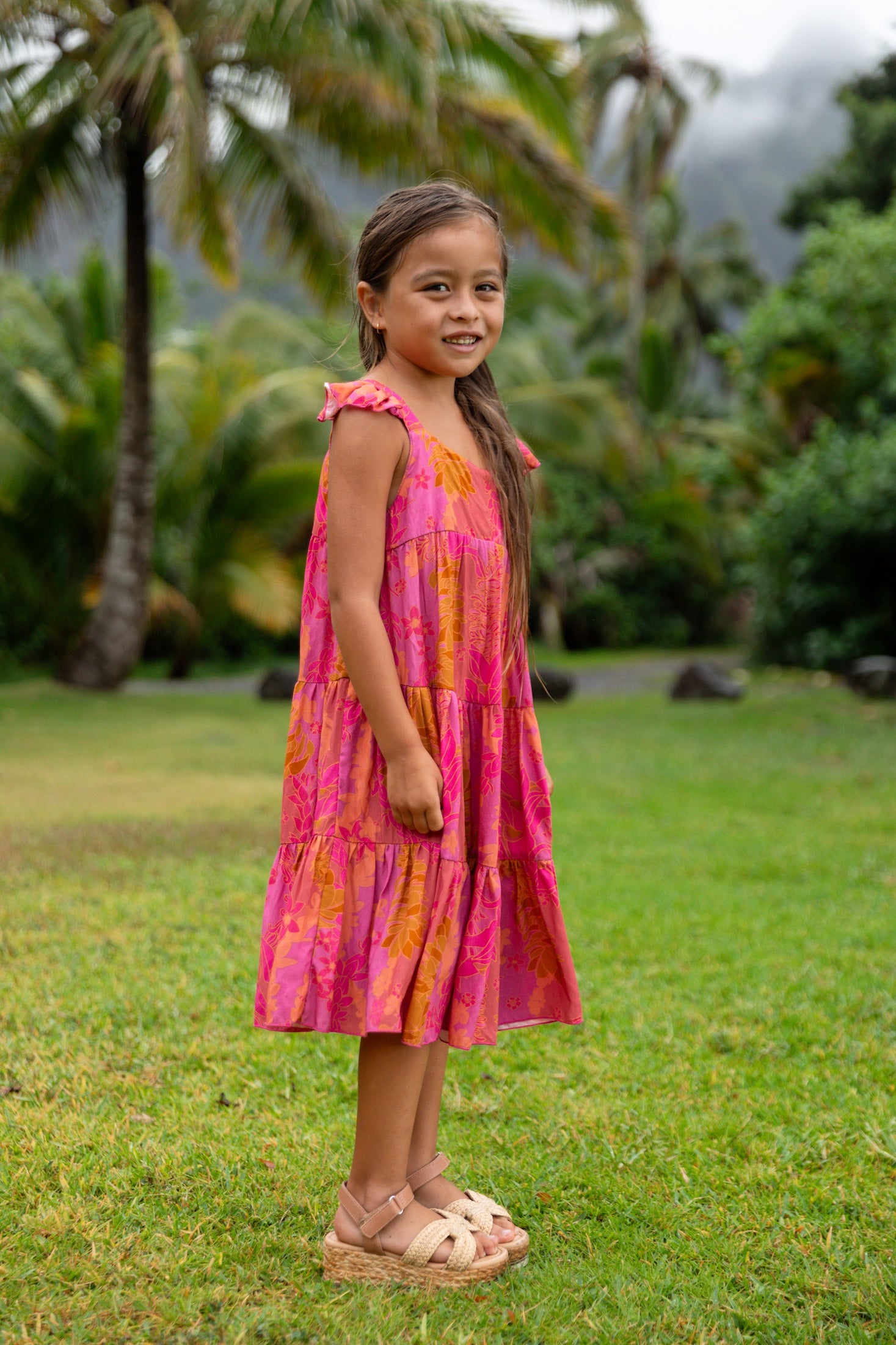 little girl wearing a long pink tiered dress with ruffle straps