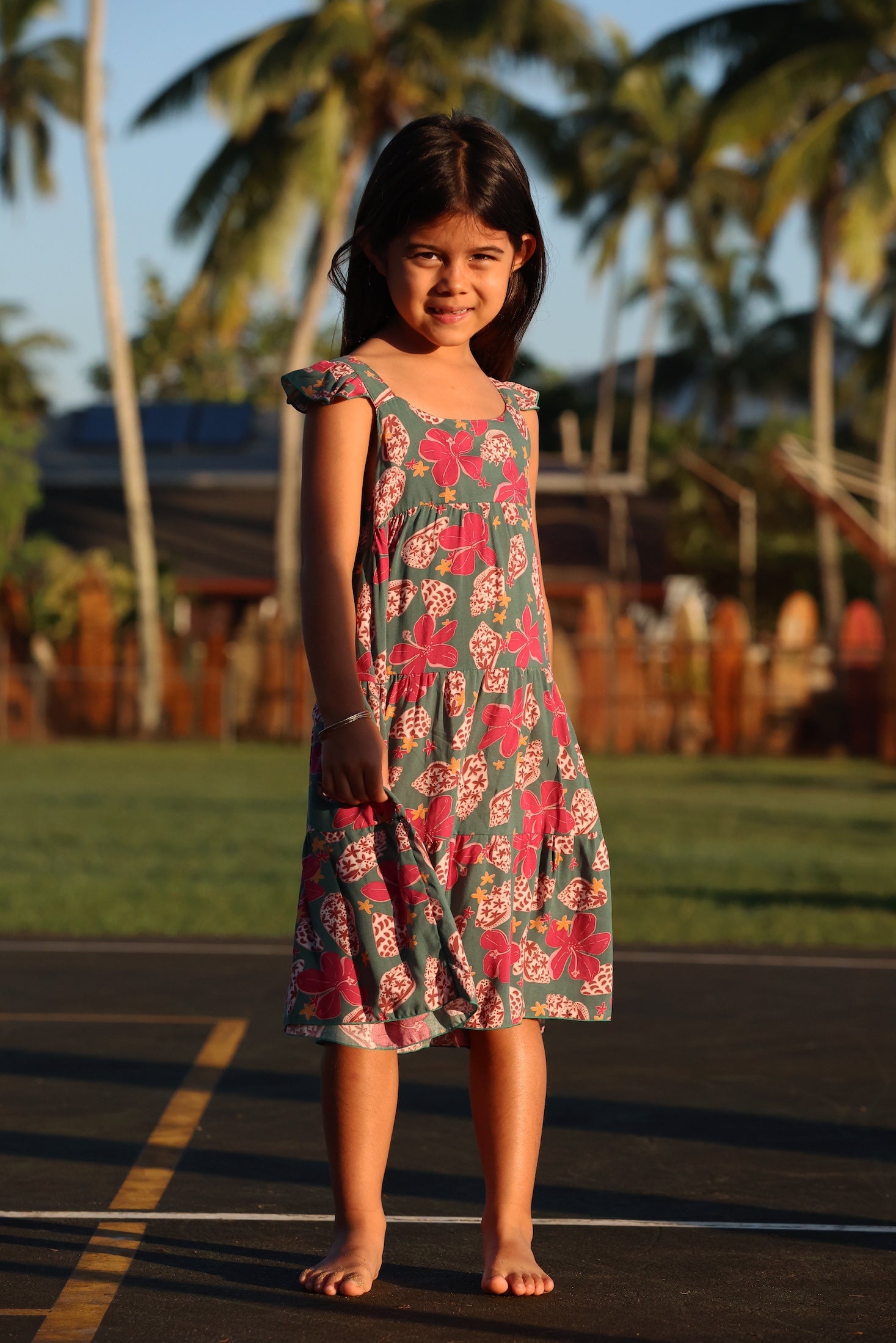 little girl wearing a teal dress with flutter sleeves with shell and pua print
