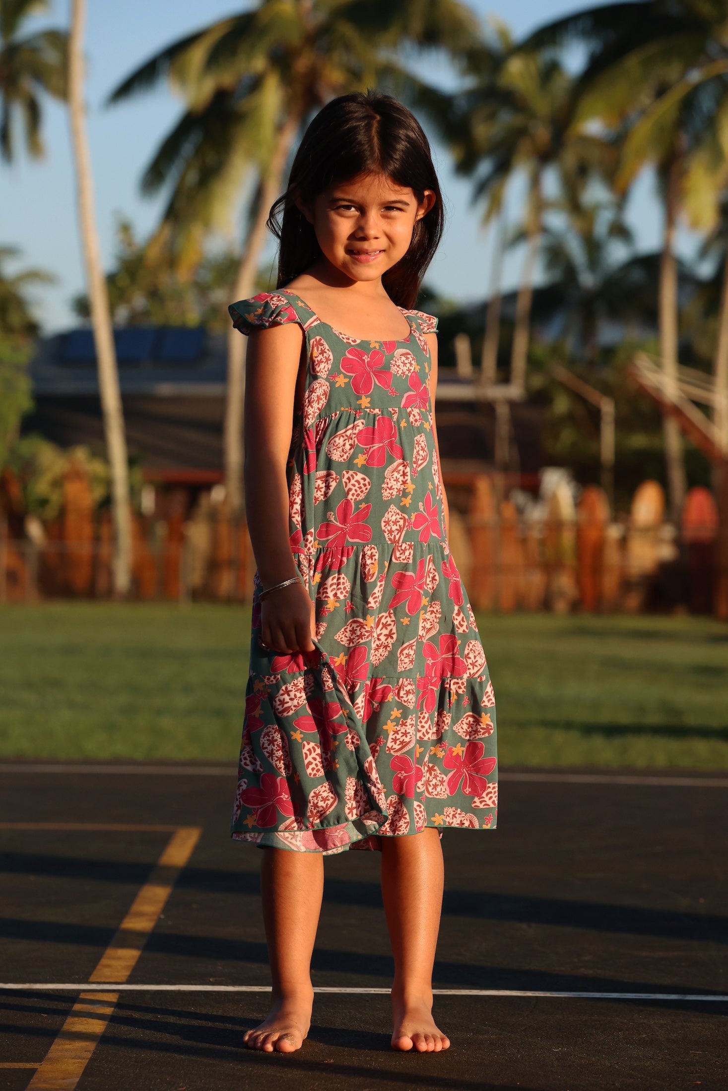 little girl wearing a teal dress with flutter sleeves with shell and pua print