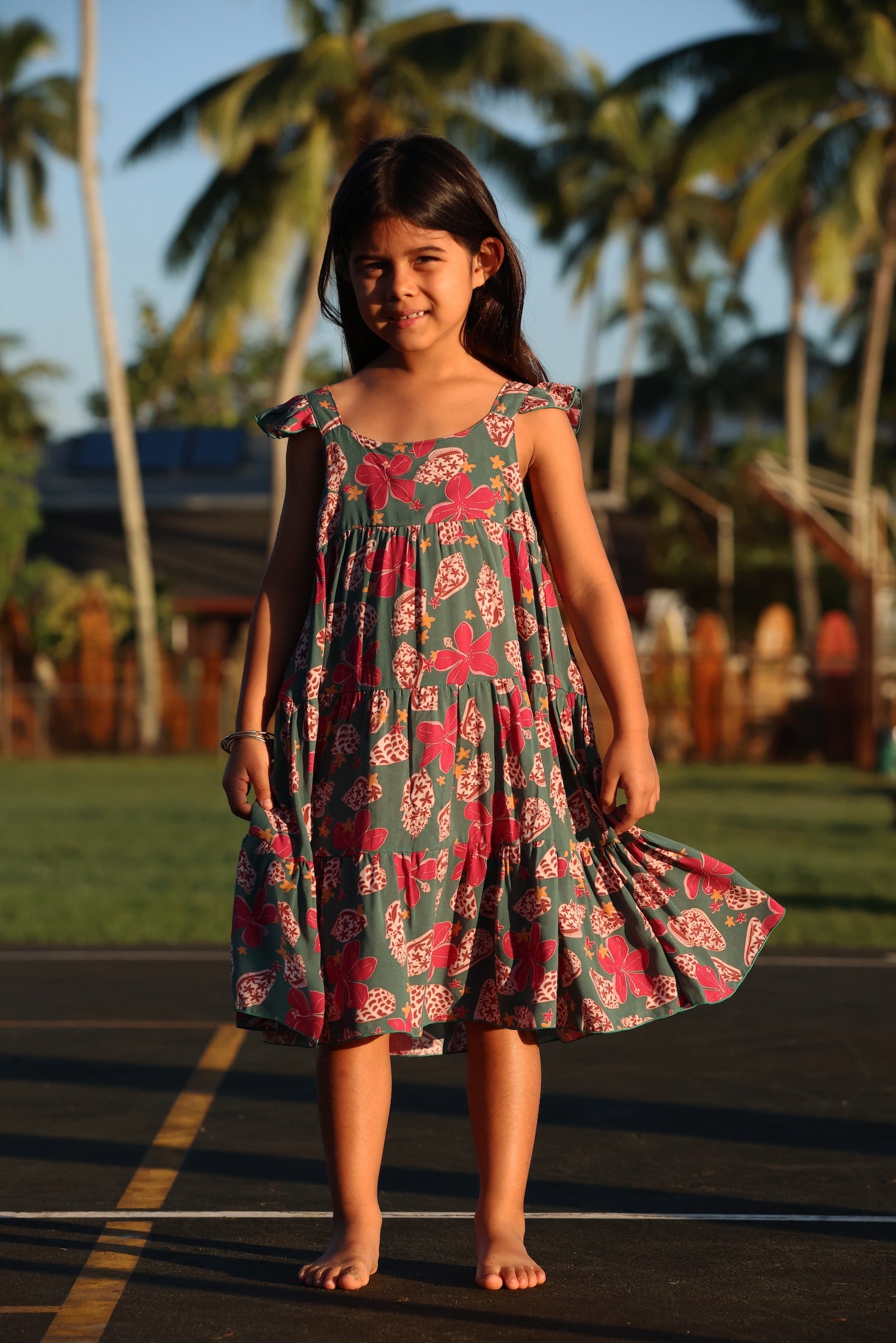 little girl wearing a teal dress with flutter sleeves with shell and pua print