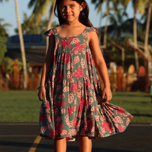 little girl wearing a teal dress with flutter sleeves with shell and pua print