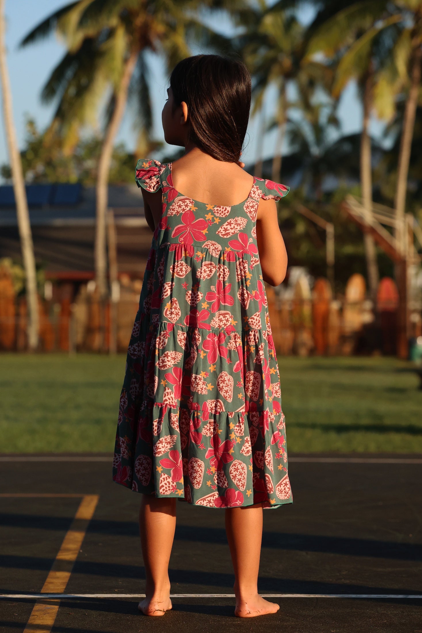little girl wearing a teal dress with flutter sleeves with shell and pua print