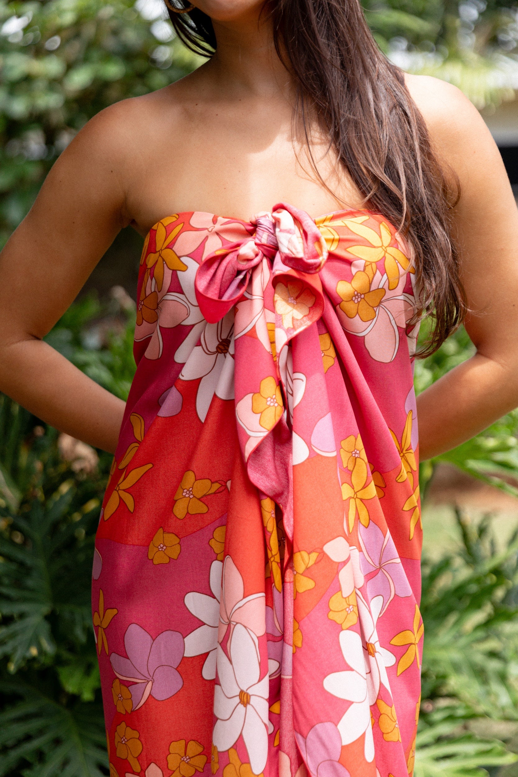 woman with brown hair wearing bright pink pareo with flower retro flower print