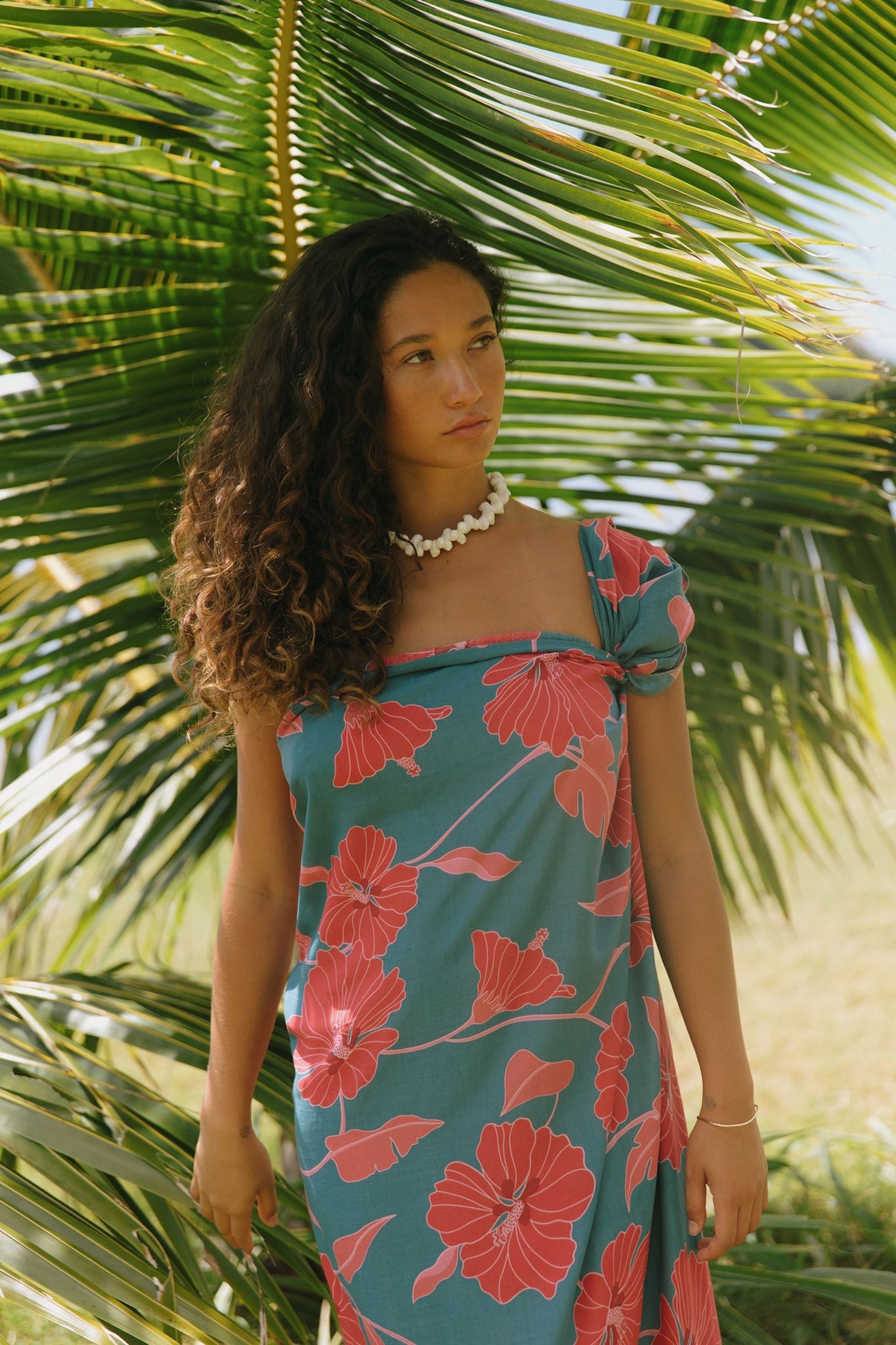woman wearing rich teal pareo with red hau flower print