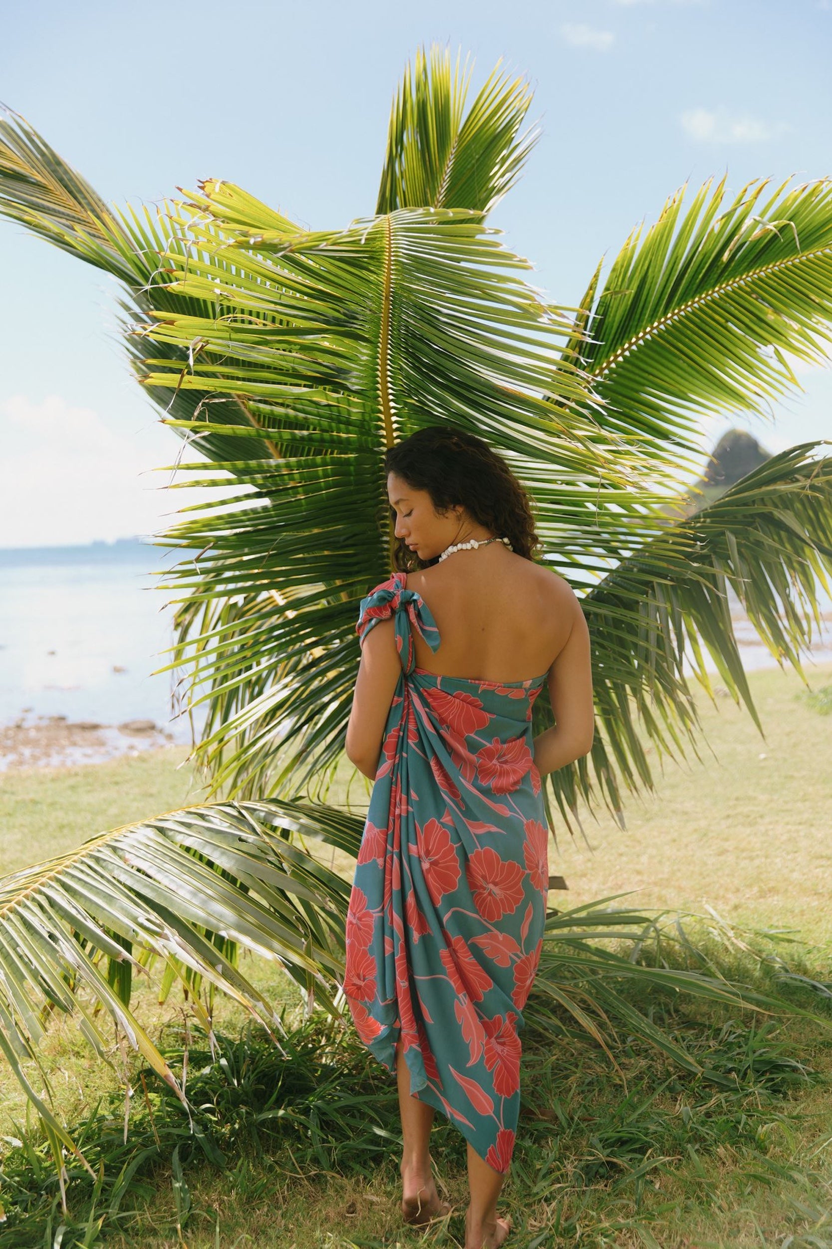 woman wearing rich teal pareo with red hau flower print