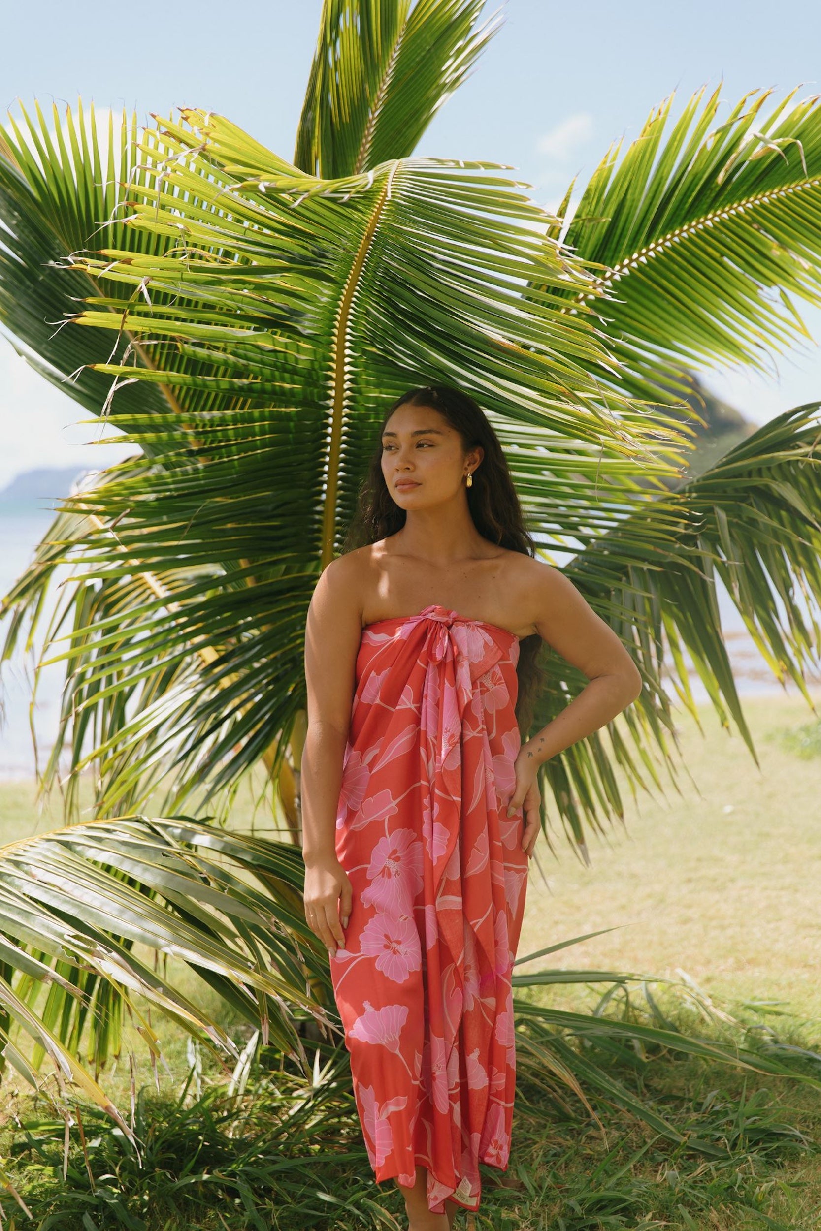 woman with brown hair wearing red pareo with pink hau flower print