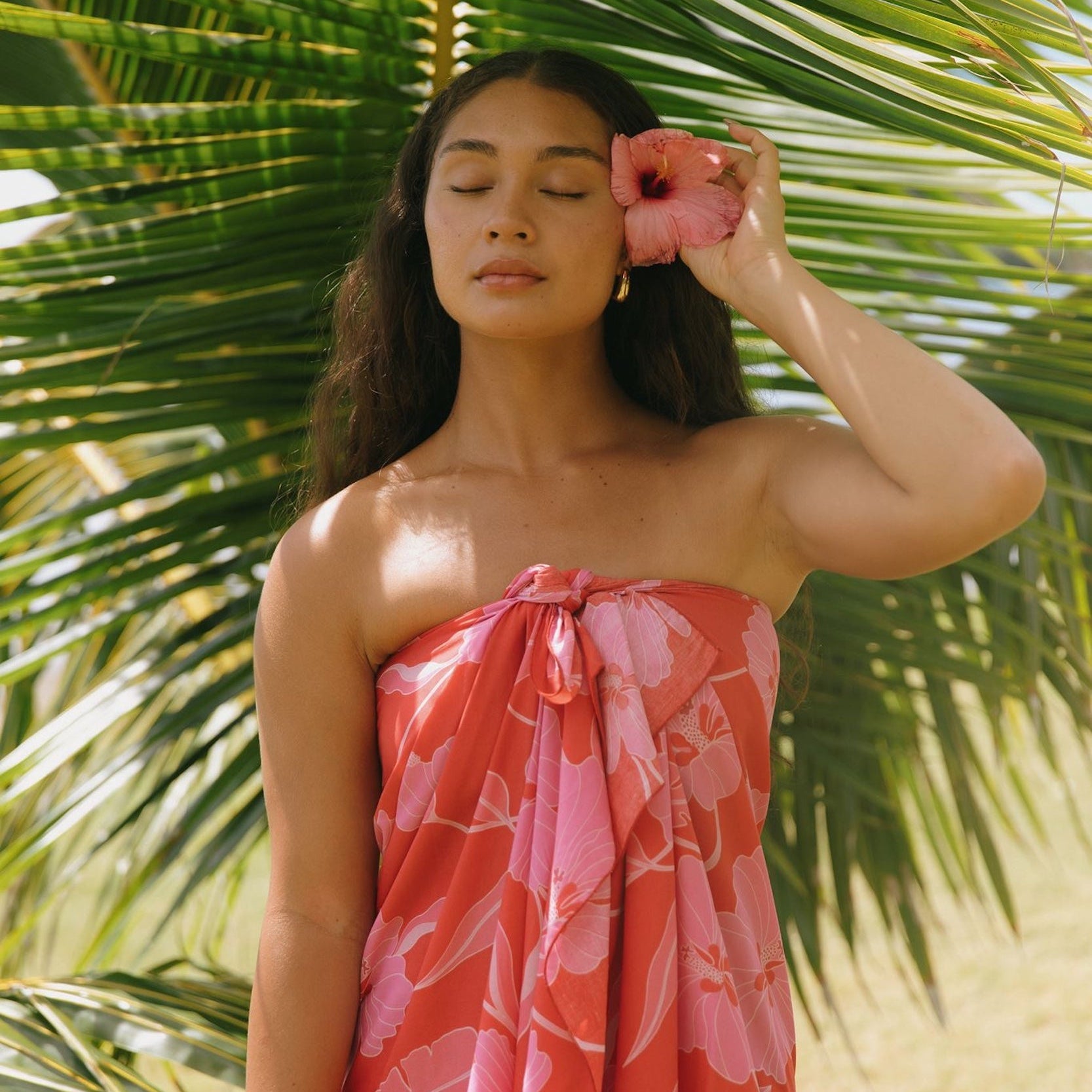 woman with brown hair wearing red pareo with pink hau flower print