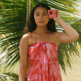 woman with brown hair wearing red pareo with pink hau flower print