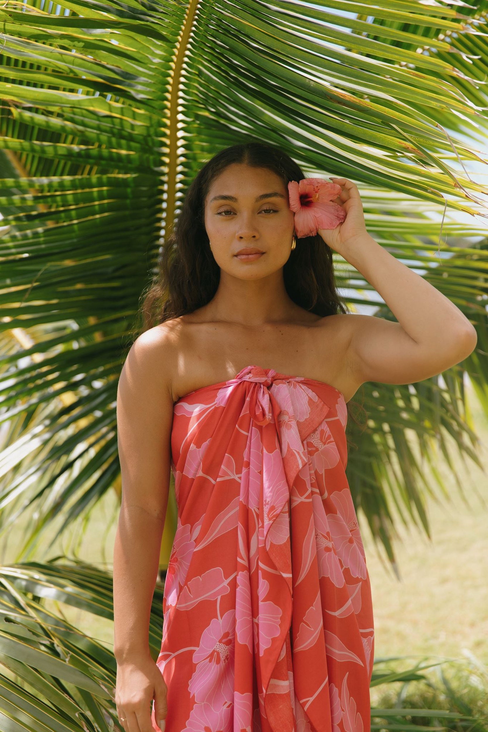woman with brown hair wearing red pareo with pink hau flower print