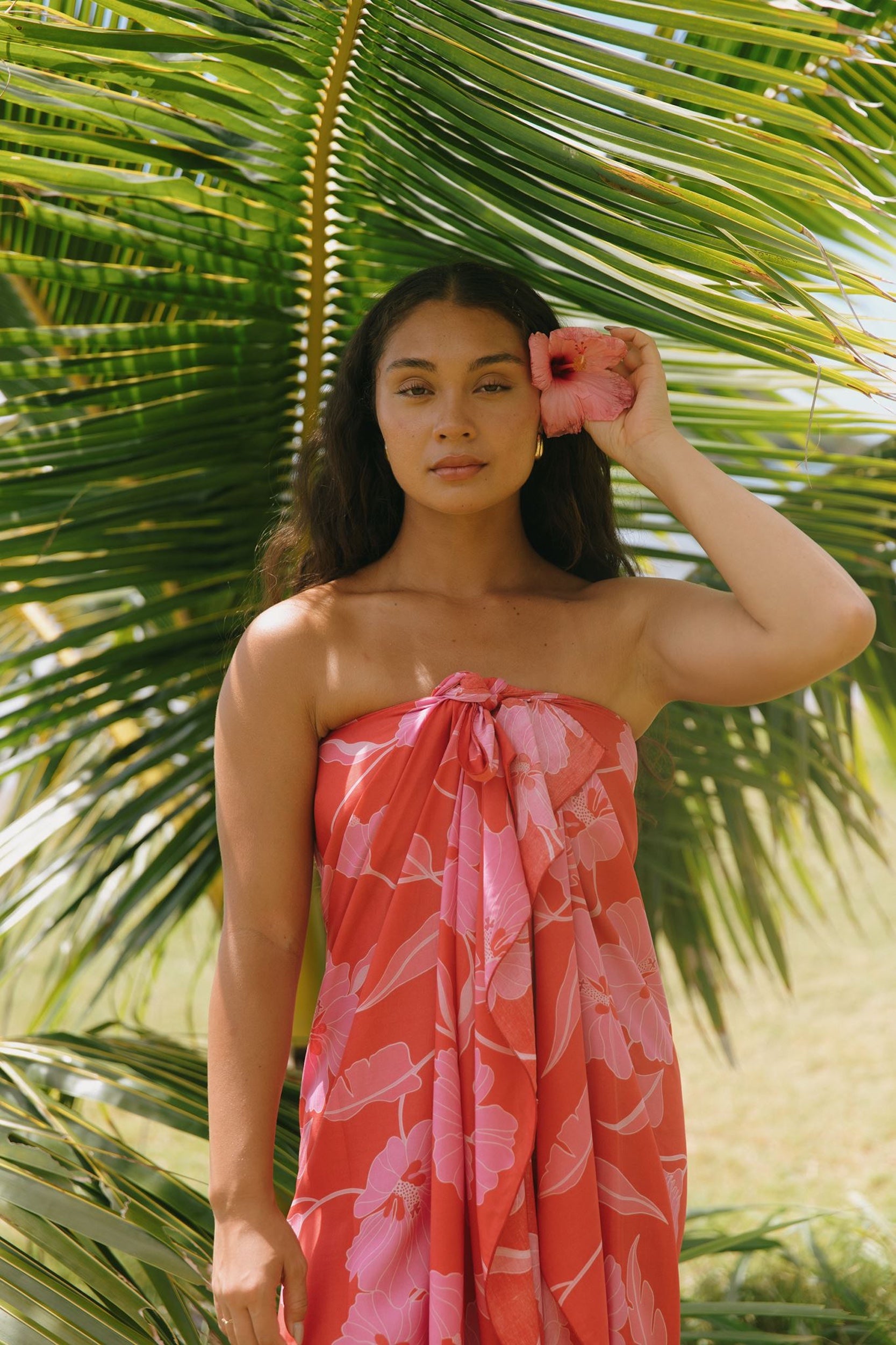 woman with brown hair wearing red pareo with pink hau flower print