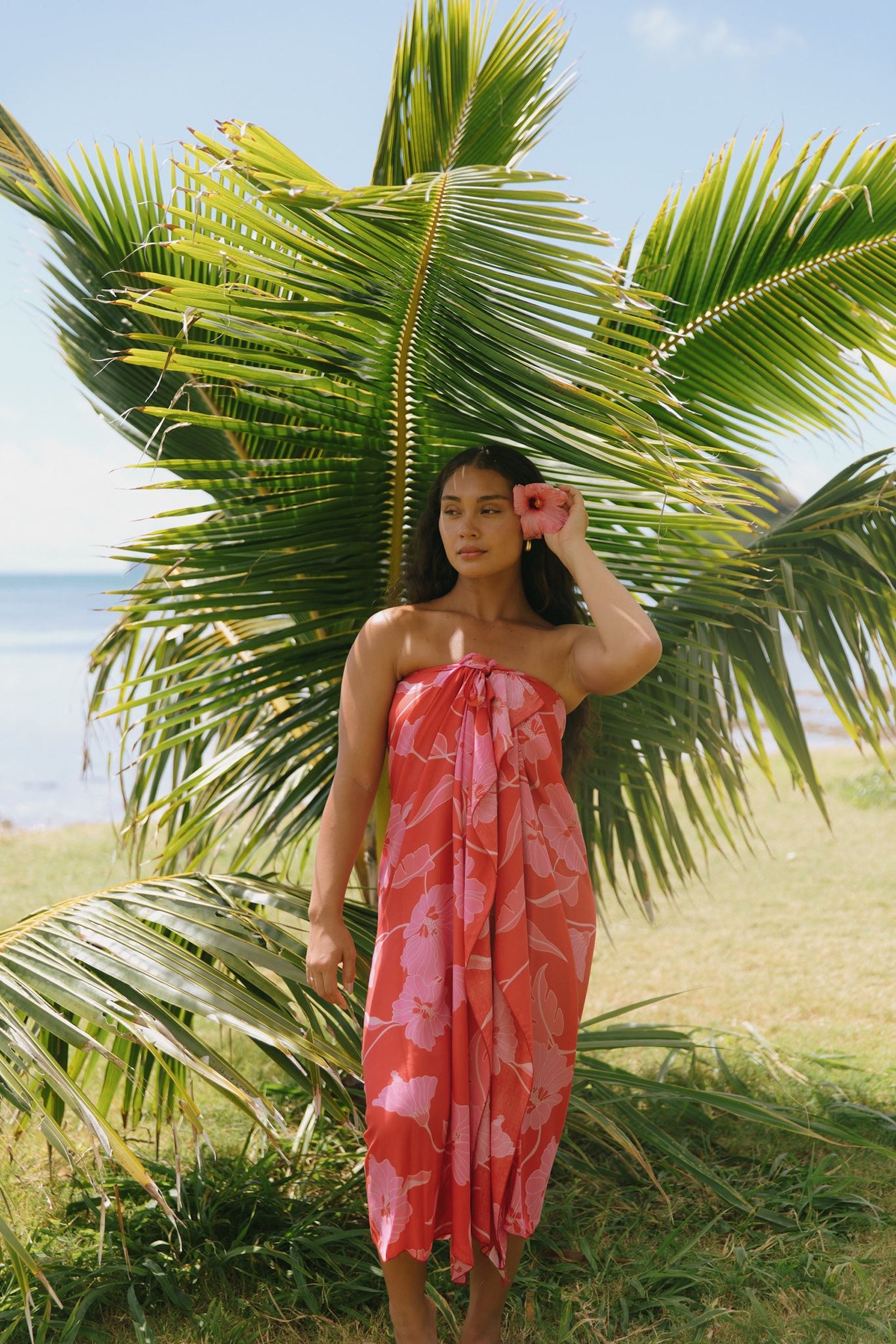 woman with brown hair wearing red pareo with pink hau flower print