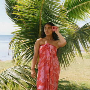 woman with brown hair wearing red pareo with pink hau flower print