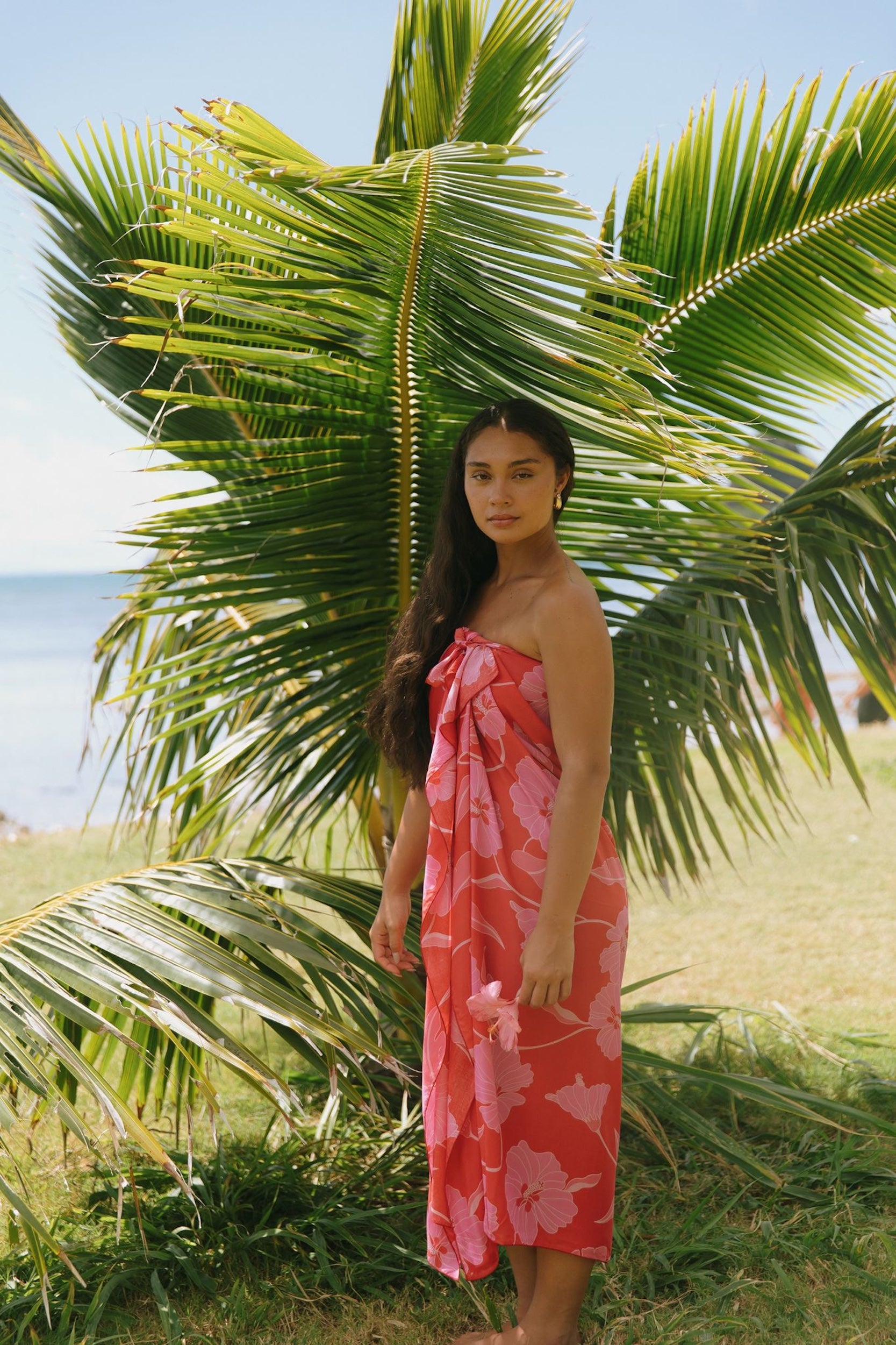 woman with brown hair wearing red pareo with pink hau flower print