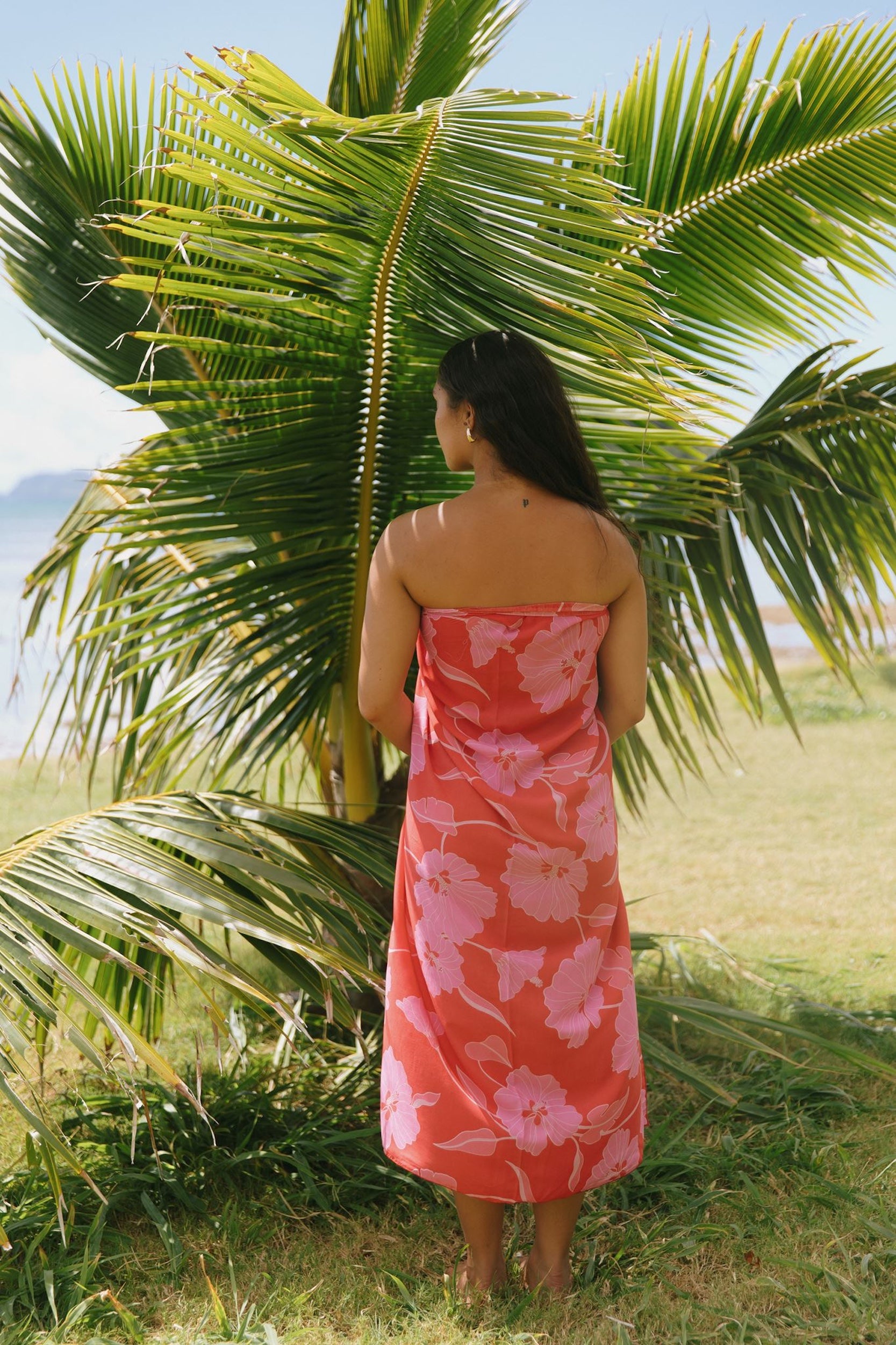 woman with brown hair wearing red pareo with pink hau flower print