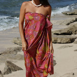 woman with brown hair wearing terracotta colored pareo with large purple and yellow flower print