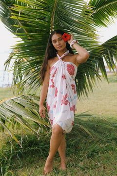 woman with brown hair wearing light white pinkish pareo with large red hibiscus print