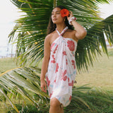 woman with brown hair wearing light white pinkish pareo with large red hibiscus print