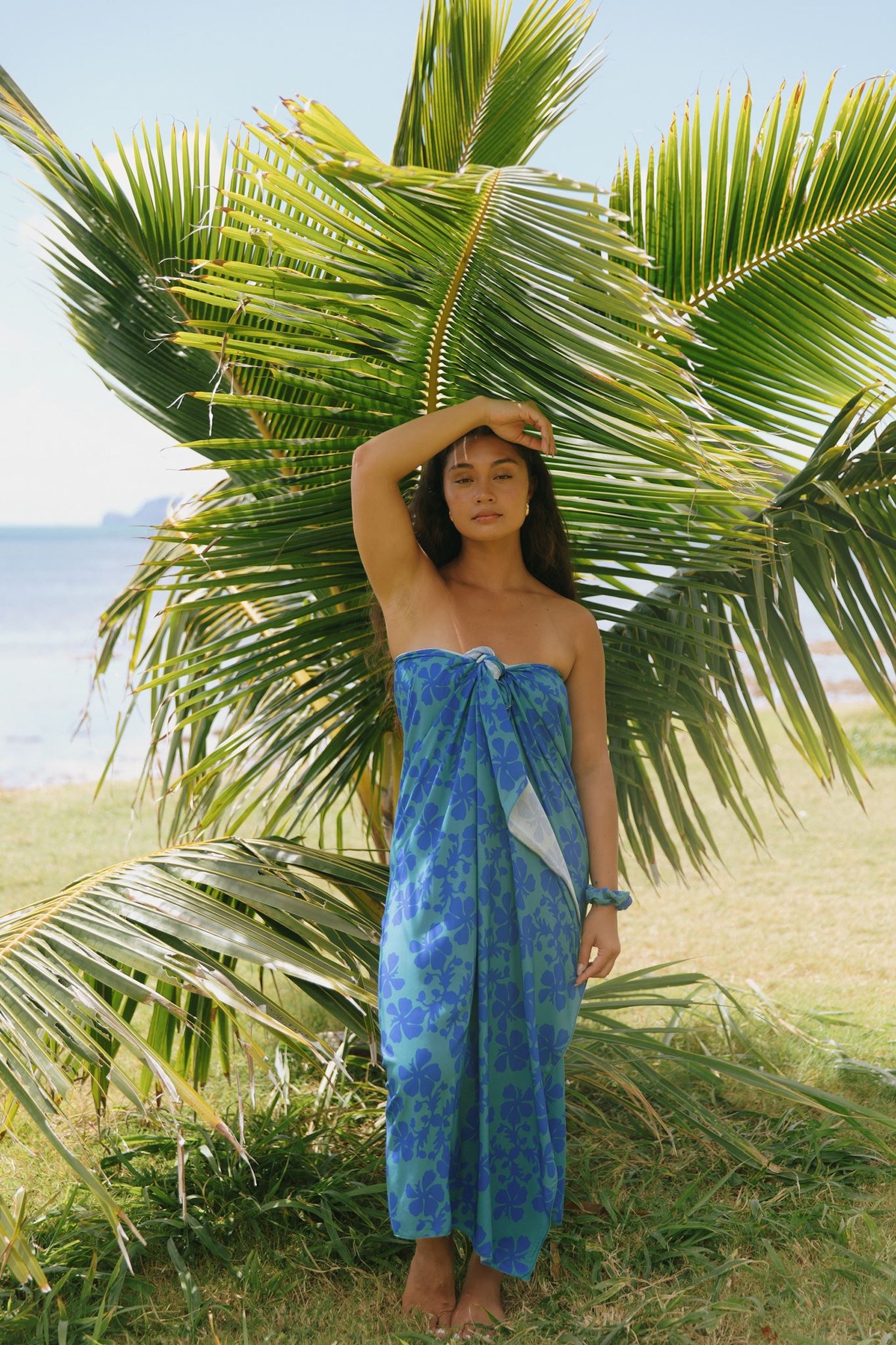 woman with brown hair wearing teal aqua pareo with blue solid hibiscus print