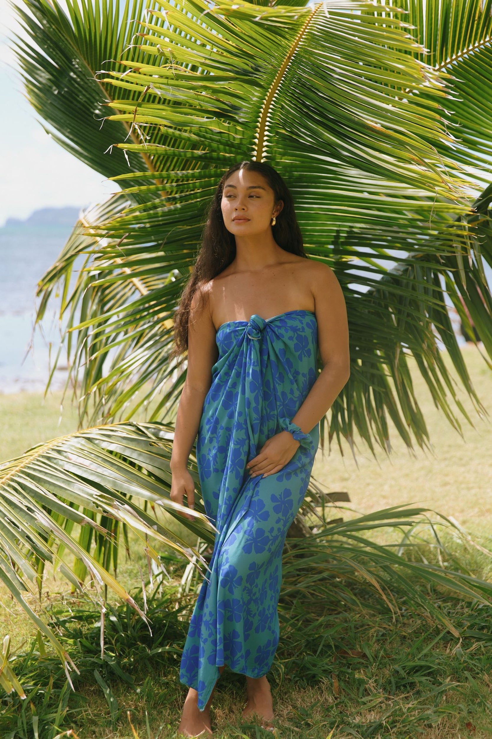 woman with brown hair wearing teal aqua pareo with blue solid hibiscus print
