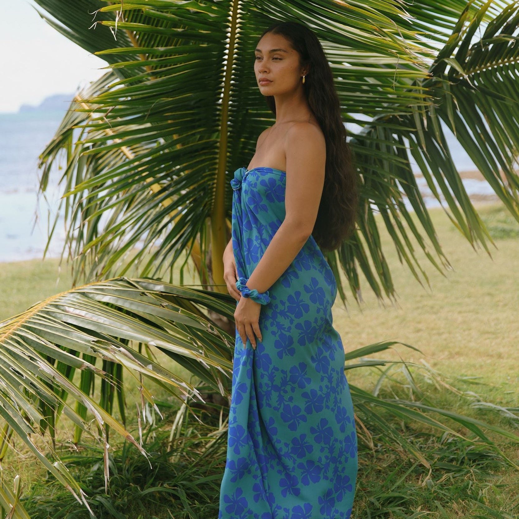 woman with brown hair wearing teal aqua pareo with blue solid hibiscus print
