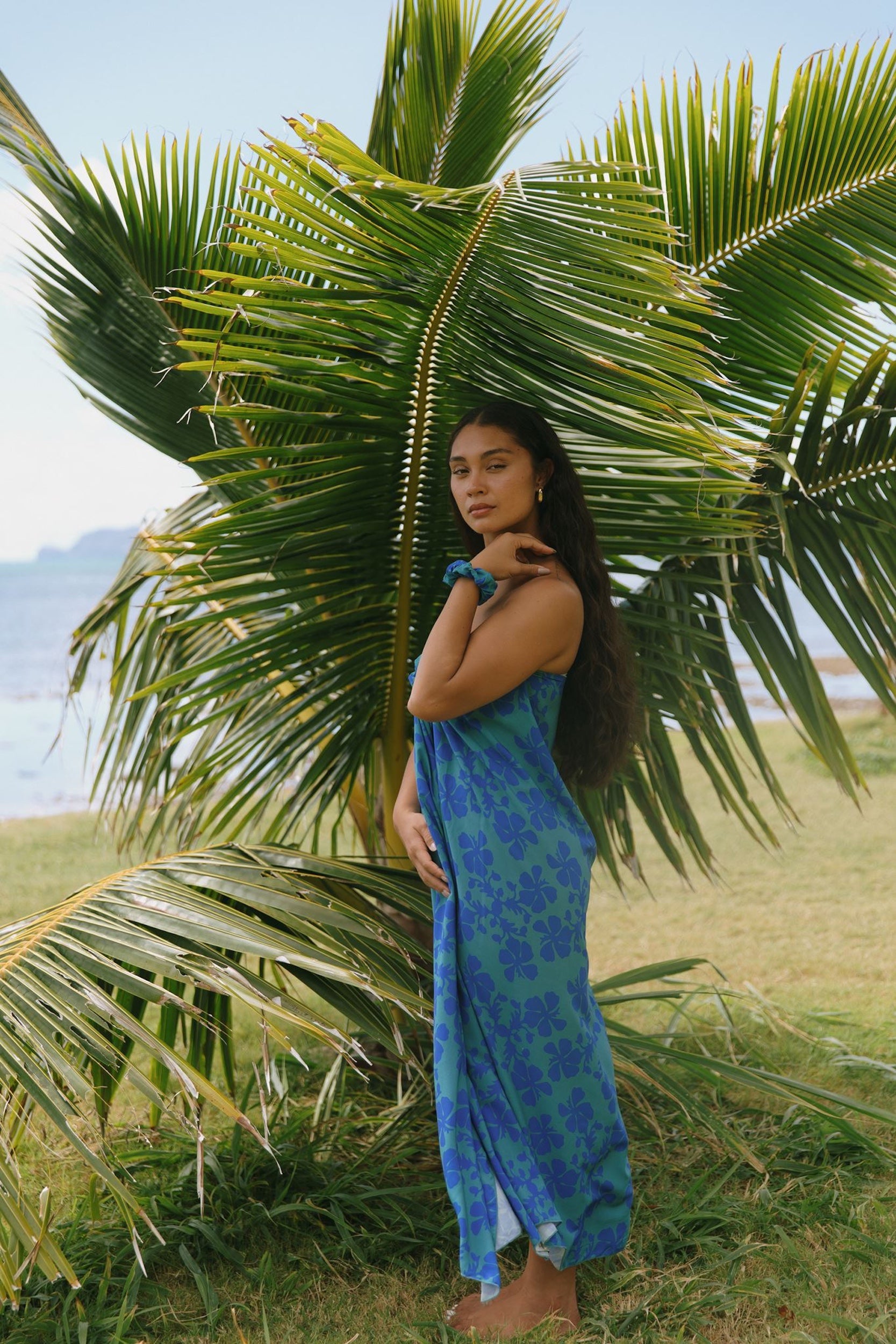 woman with brown hair wearing teal aqua pareo with blue solid hibiscus print