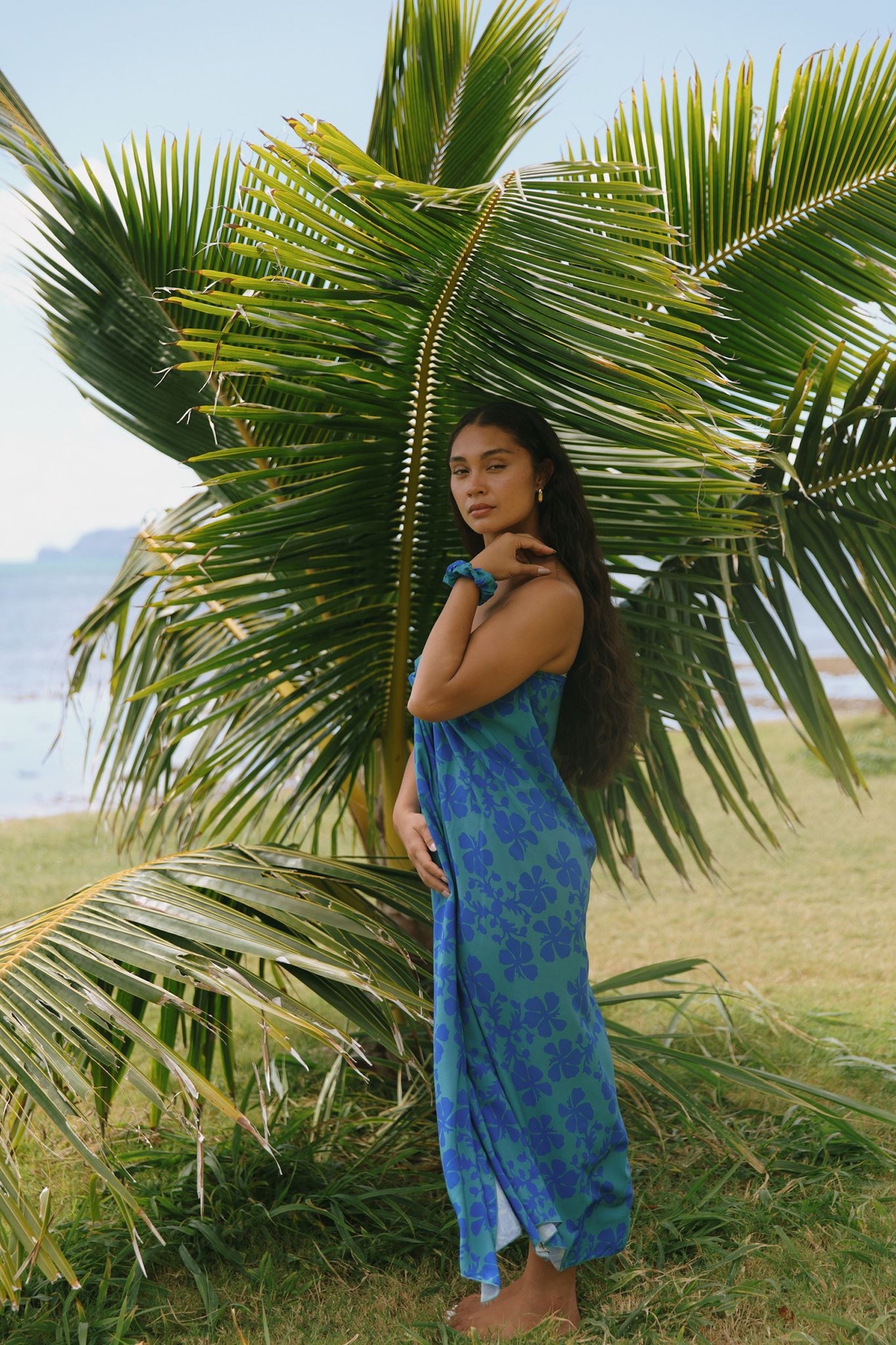woman with brown hair wearing teal aqua pareo with blue solid hibiscus print