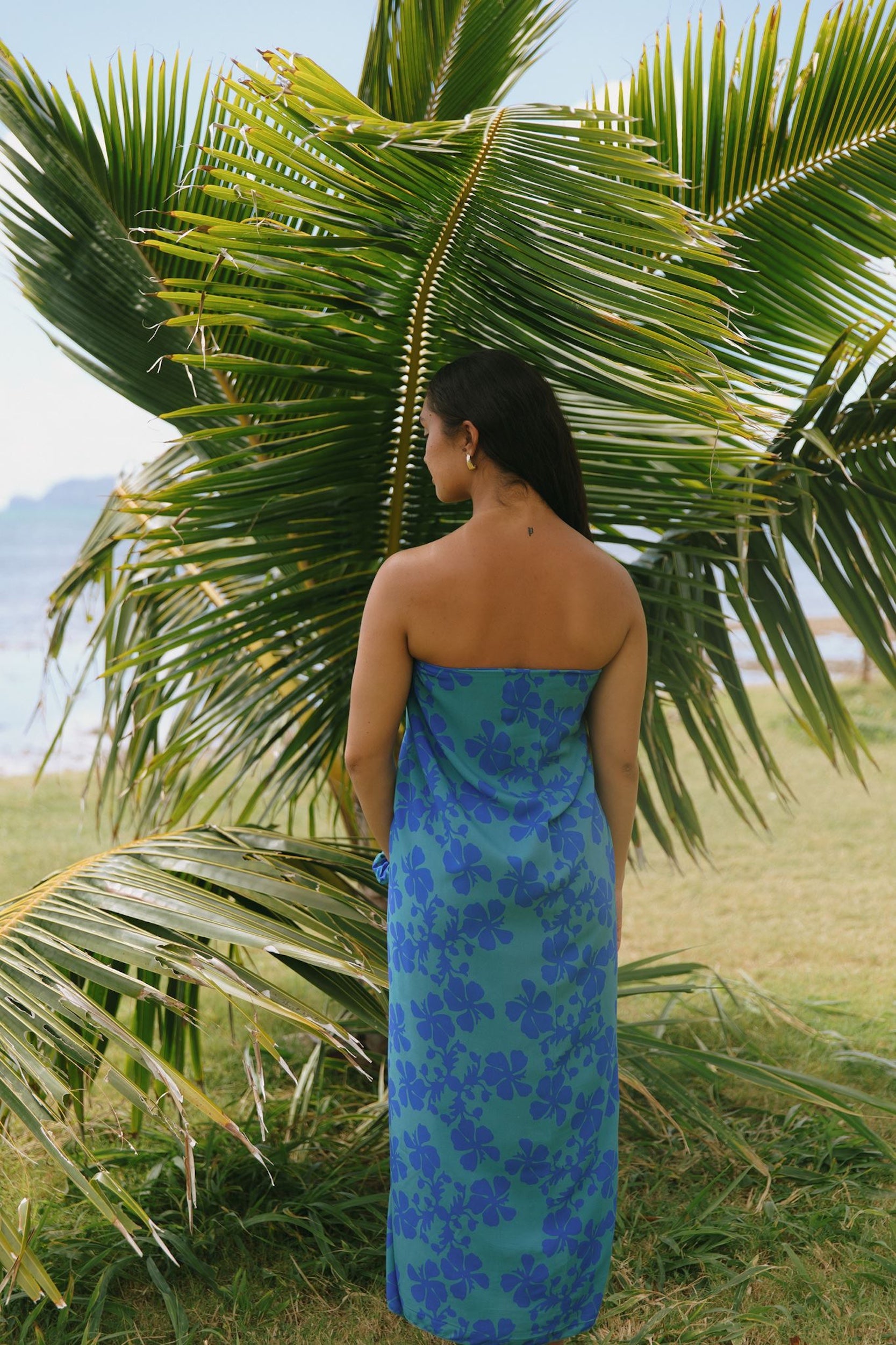 woman with brown hair wearing teal aqua pareo with blue solid hibiscus print