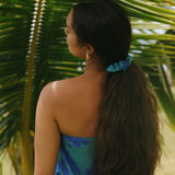 woman with brown hair wearing teal scrunchie with dark blue hibiscus print
