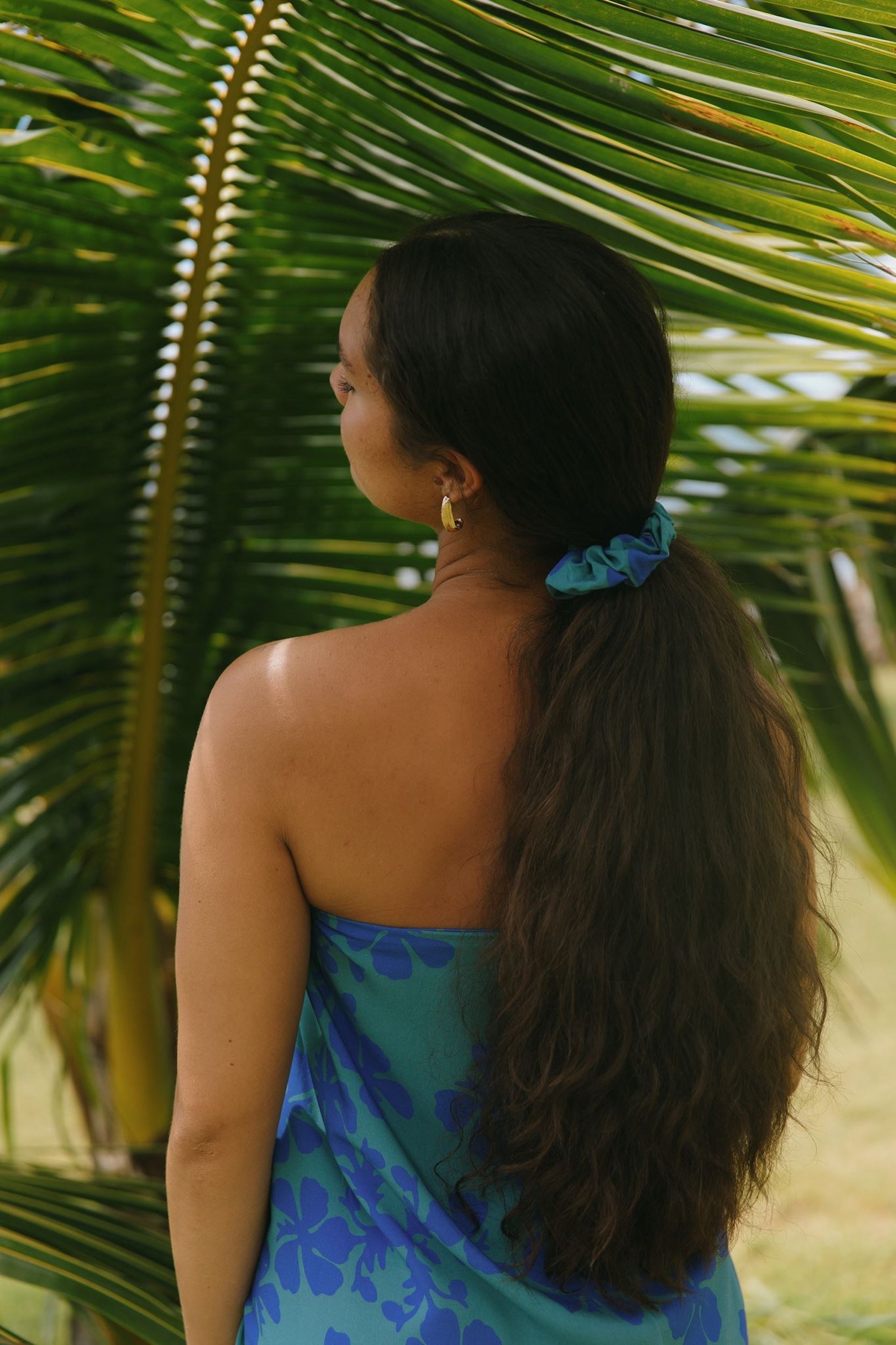 woman with brown hair wearing teal scrunchie with dark blue hibiscus print