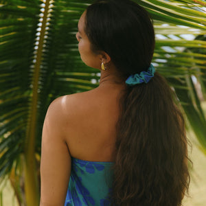 woman with brown hair wearing teal scrunchie with dark blue hibiscus print