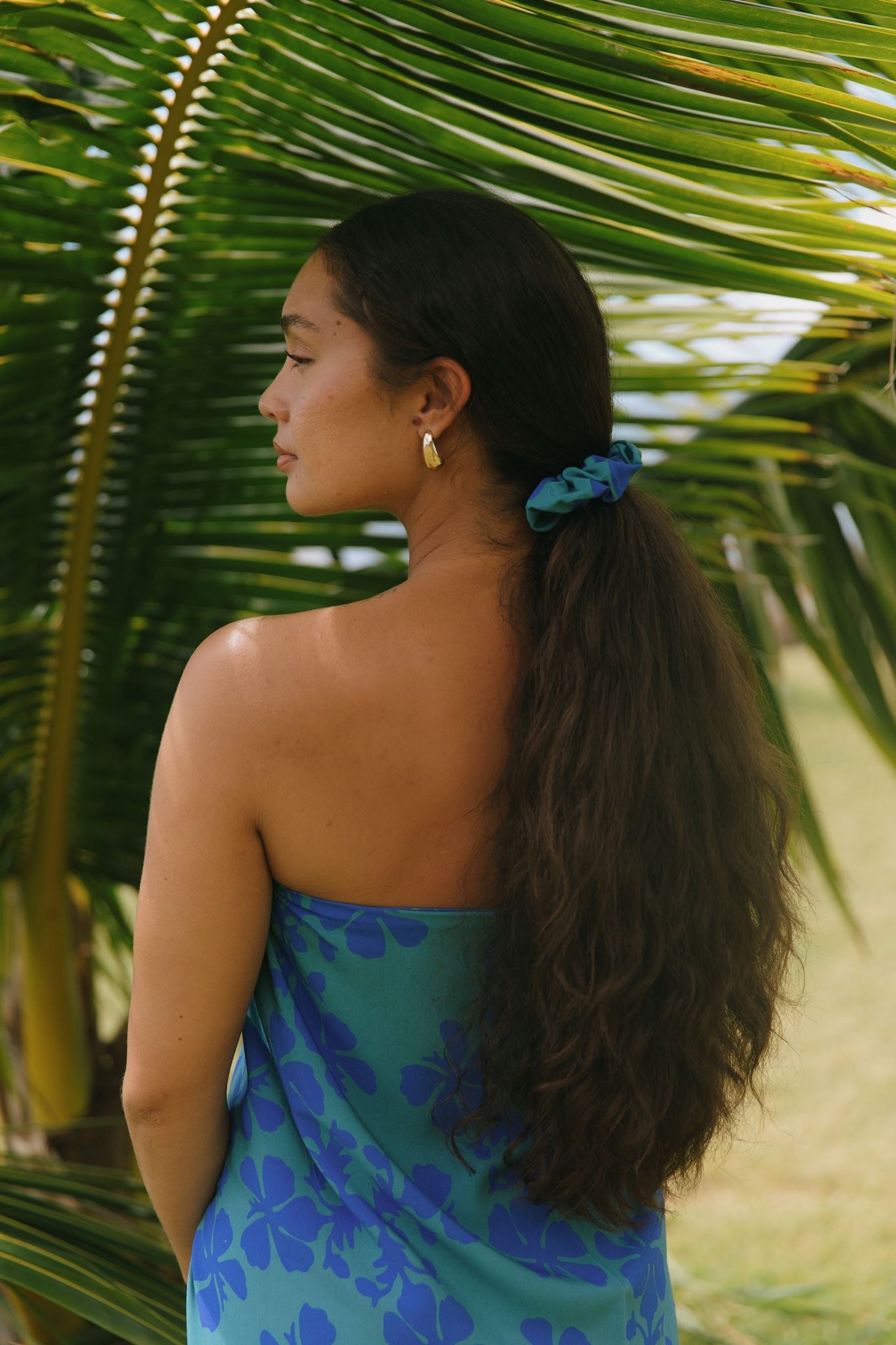 woman with brown hair wearing teal scrunchie with dark blue hibiscus print