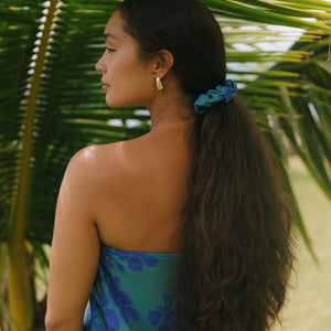 woman with brown hair wearing teal scrunchie with dark blue hibiscus print