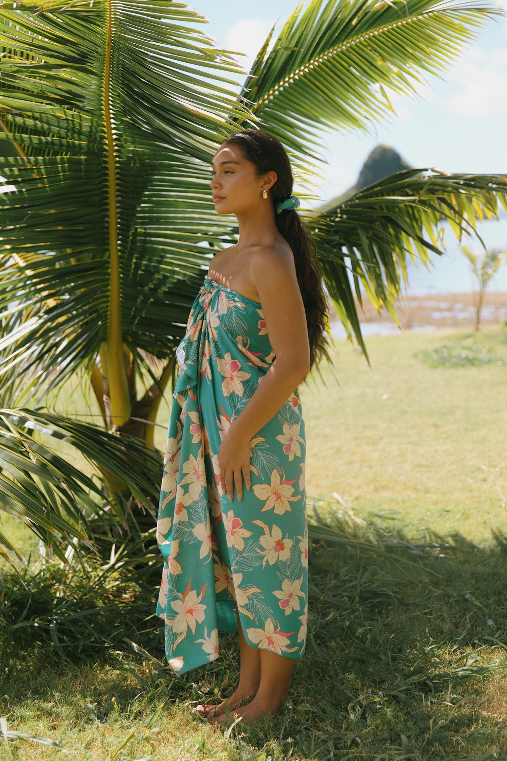 woman with brown hair wearing teal pareo with orchid print