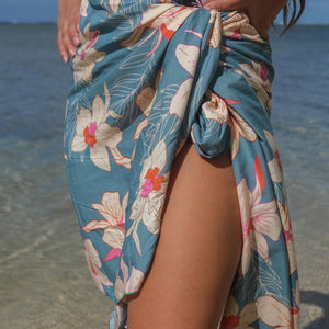 woman wearing a teal pareo with cream colored orchid pattern