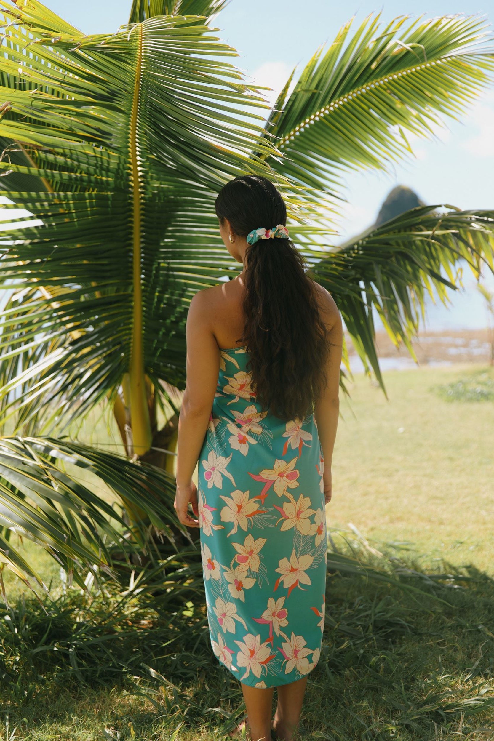 woman with brown hair wearing teal pareo with orchid print
