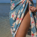 woman wearing a teal pareo with cream colored orchid pattern