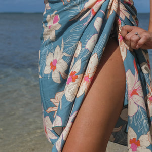 woman wearing a teal pareo with cream colored orchid pattern