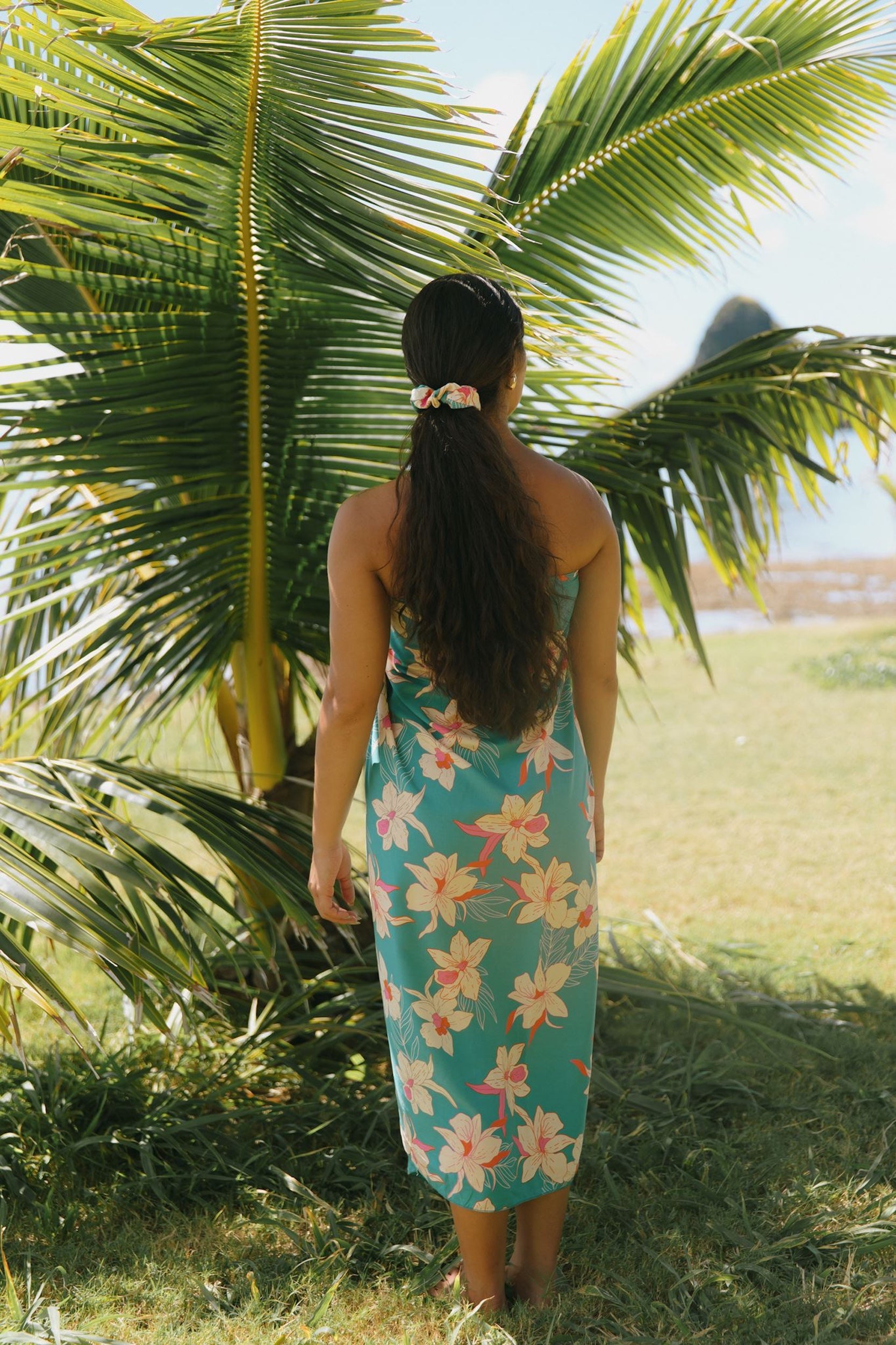 woman with brown hair wearing teal pareo with orchid print