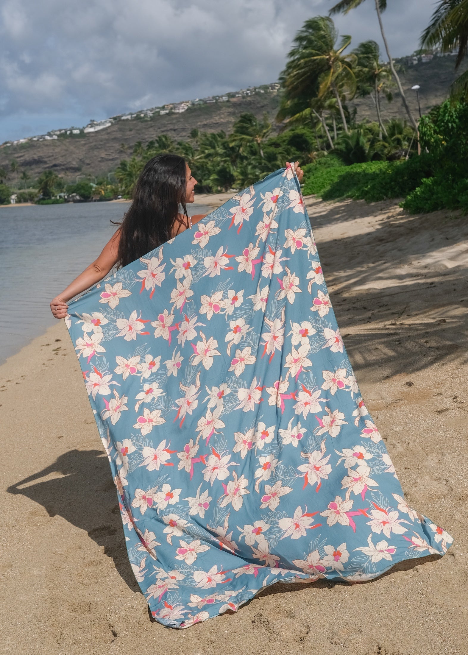 woman wearing a teal pareo with cream colored orchid pattern