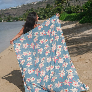 woman wearing a teal pareo with cream colored orchid pattern