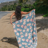 woman wearing a teal pareo with cream colored orchid pattern