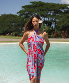 woman with brown hair wearing a pareo with periwinkle background and bright red hibiscus print.