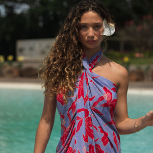 woman with brown hair wearing a pareo with periwinkle background and bright red hibiscus print.