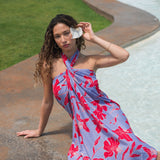 woman with brown hair wearing a pareo with periwinkle background and bright red hibiscus print.