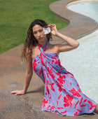 woman with brown hair wearing a pareo with periwinkle background and bright red hibiscus print.