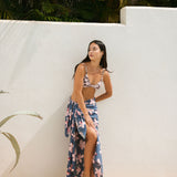 woman with black hair wearing a pareo in a navy and pink hibiscus print. 
