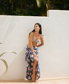 woman with black hair wearing a pareo in a navy and pink hibiscus print. 